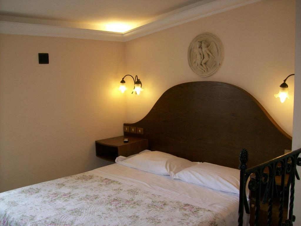 罗马普拉蒂酒店的一间卧室配有一张带木制床头板和灯的床。