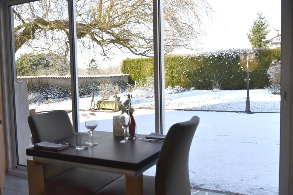 DelmeLogis Restaurant & Hôtel À la 12的一张桌子和两杯酒,享有雪盖庭院的景色