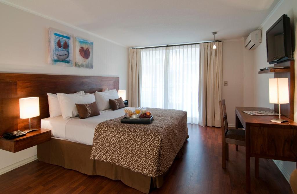 圣地亚哥公园广场公寓酒店的一间卧室配有一张带书桌和电视的床。