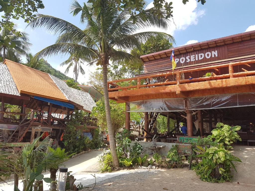 涛岛波塞冬度假村的一座楼前有棕榈树的餐厅
