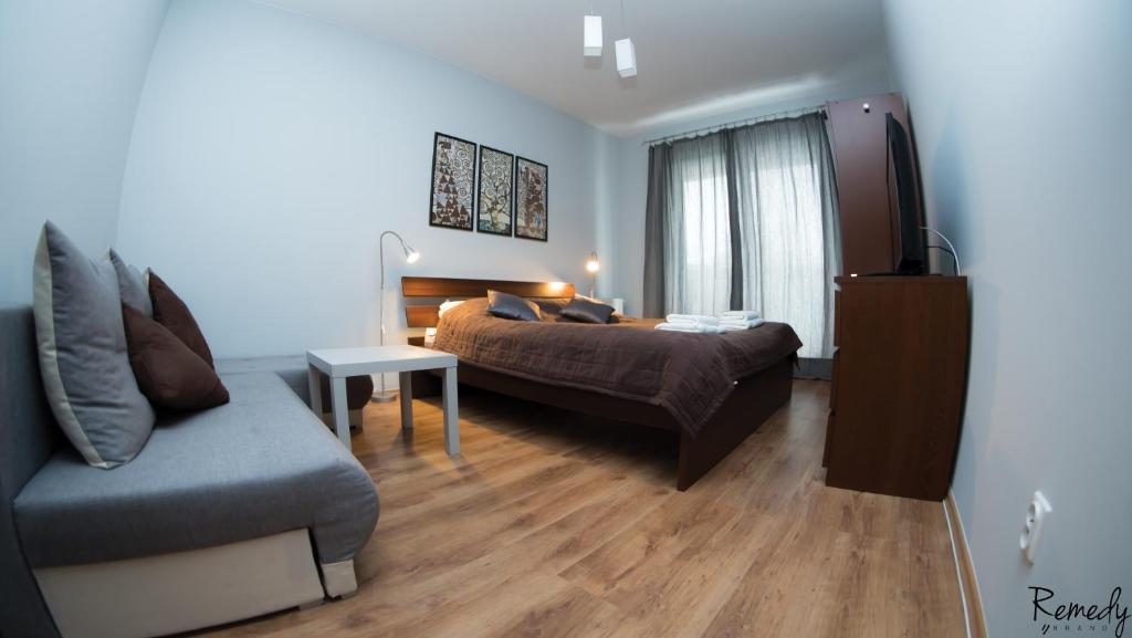 什切青Apartamenty Sedinum - Modern的一间卧室配有一张床、一张沙发和一张桌子