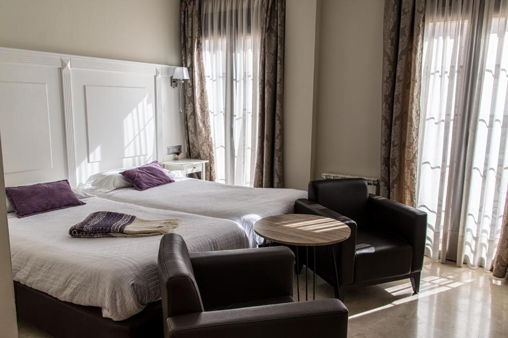 隆达塞维利亚酒店的一间卧室配有一张床、两把椅子和一张桌子