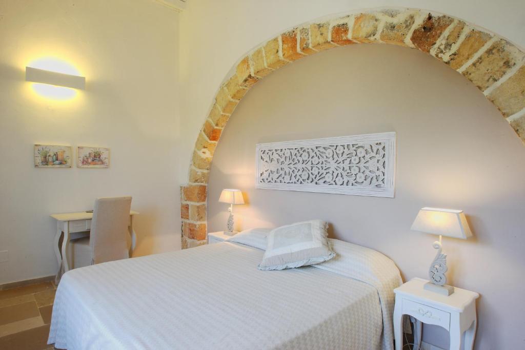 科佩尔蒂诺Masseria La Tofala benessere & SPA的卧室配有白色的床和砖墙