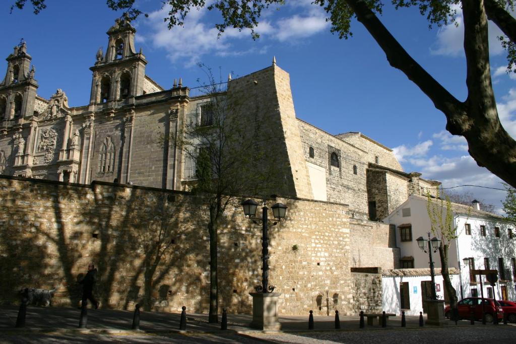 乌贝达Hostal Santa María de Úbeda的一座古老的石头建筑,后面有一座教堂