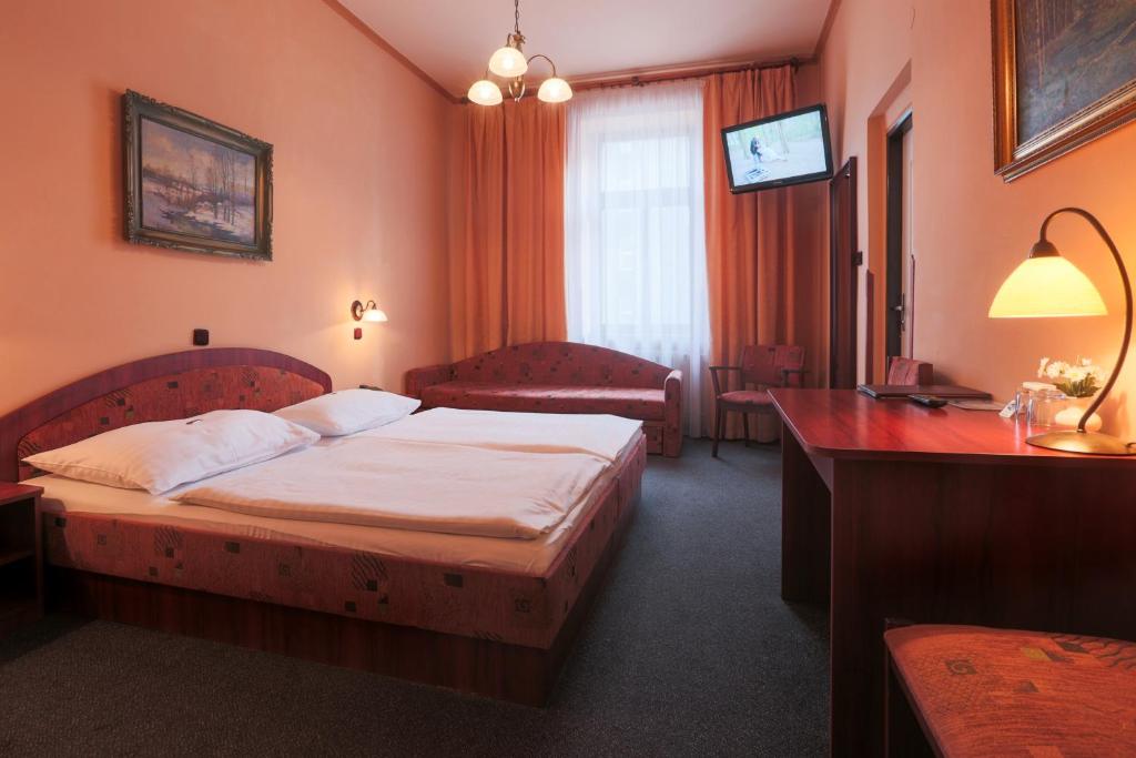 比尔森维多利亚酒店的配有一张床和一张书桌的酒店客房