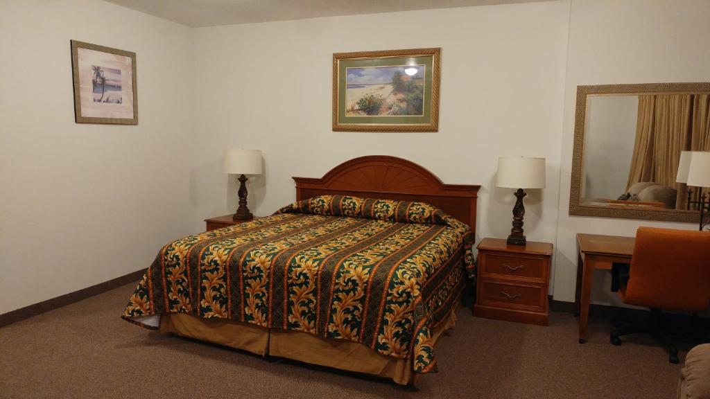 Manvel乡村丽晶酒店及套房的一间卧室配有一张床、一张书桌和一面镜子
