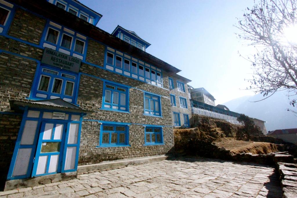 Nāmche BāzārHimalayan Lodge的一座拥有蓝色窗户和石头庭院的建筑