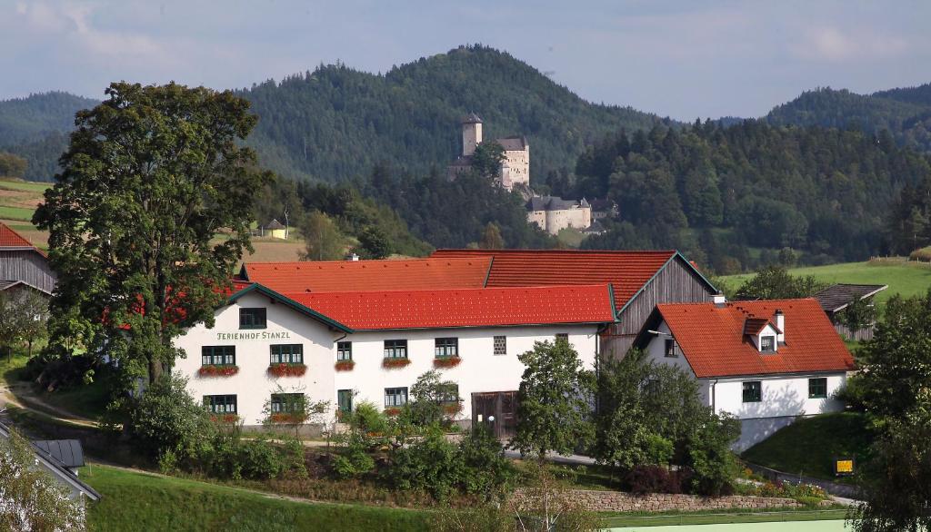 Rappottenstein费里恩霍夫斯坦泽尔住宿加早餐旅馆的一座白色的房子,有红色的屋顶,后面有一座城堡