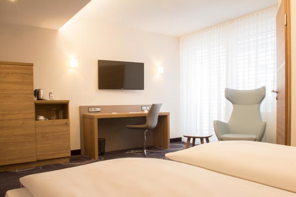 卡尔斯鲁厄里约酒店的酒店客房配有书桌和电视。