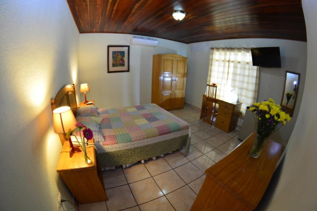 马那瓜Hotel Posada Don Pantaleon的一间卧室配有一张床和一张鲜花桌