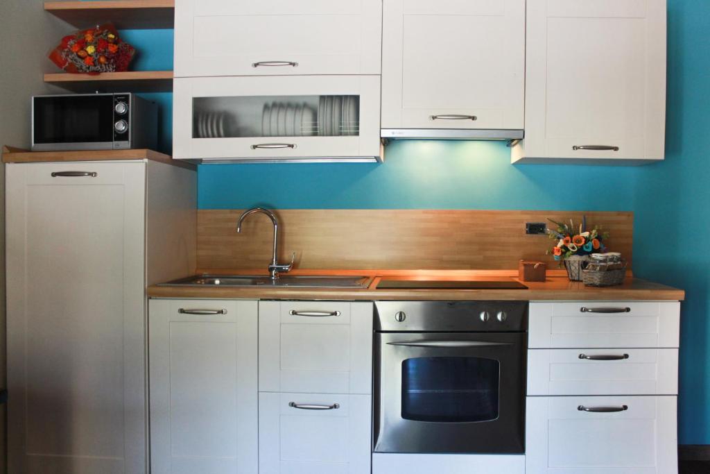 奥斯塔Dimora delle Alpi的厨房配有白色橱柜和炉灶烤箱。