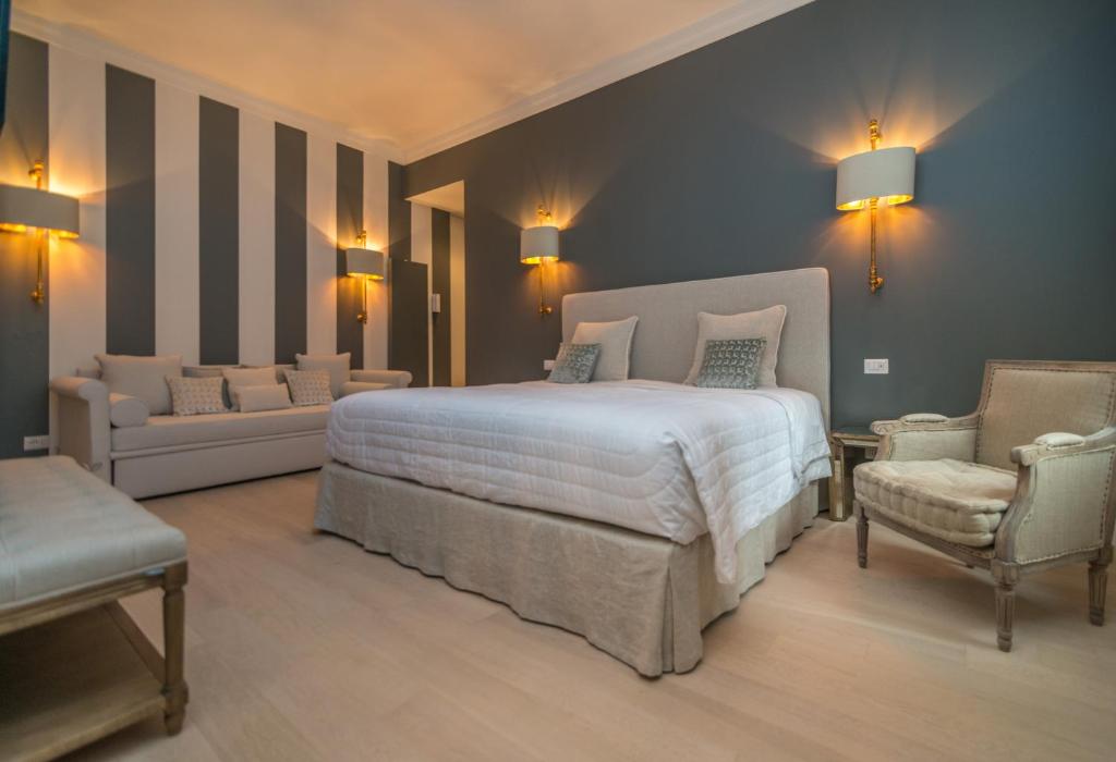 米兰布雷拉奢华套房公寓的一间卧室配有一张床、一张沙发和一把椅子