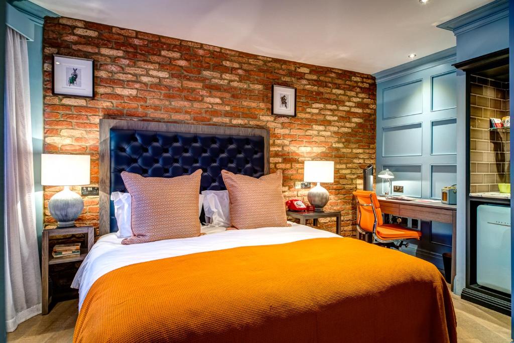 雷丁The Great House, Sonning, Berkshire的一间卧室设有一张大床和砖墙