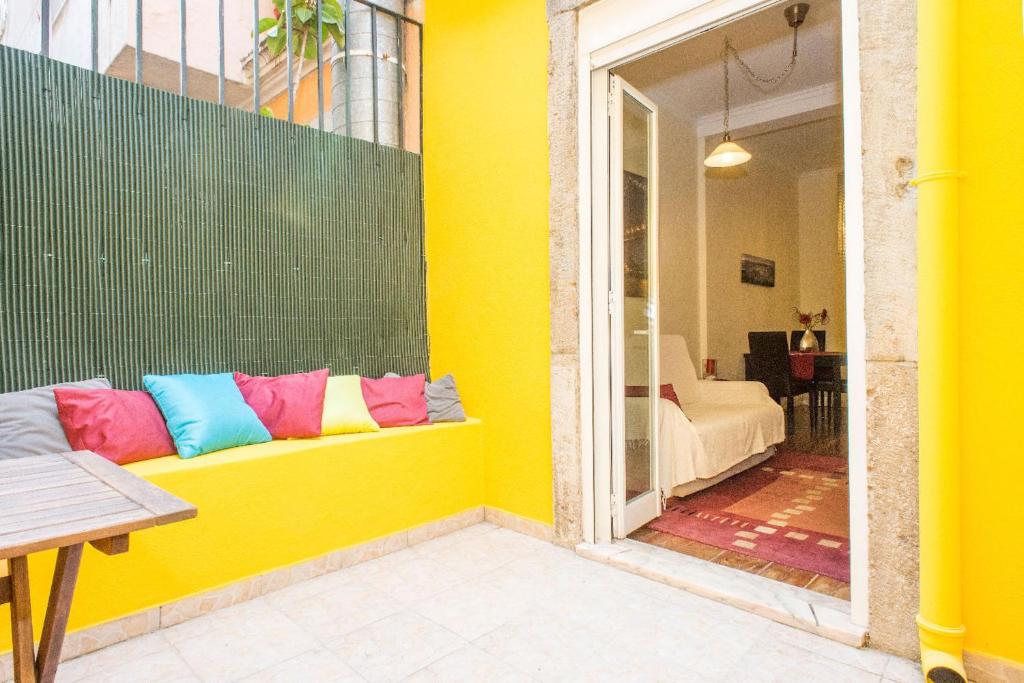 里斯本Find Me Inn Alcantara的黄色的墙壁,上面有长凳和色彩缤纷的枕头
