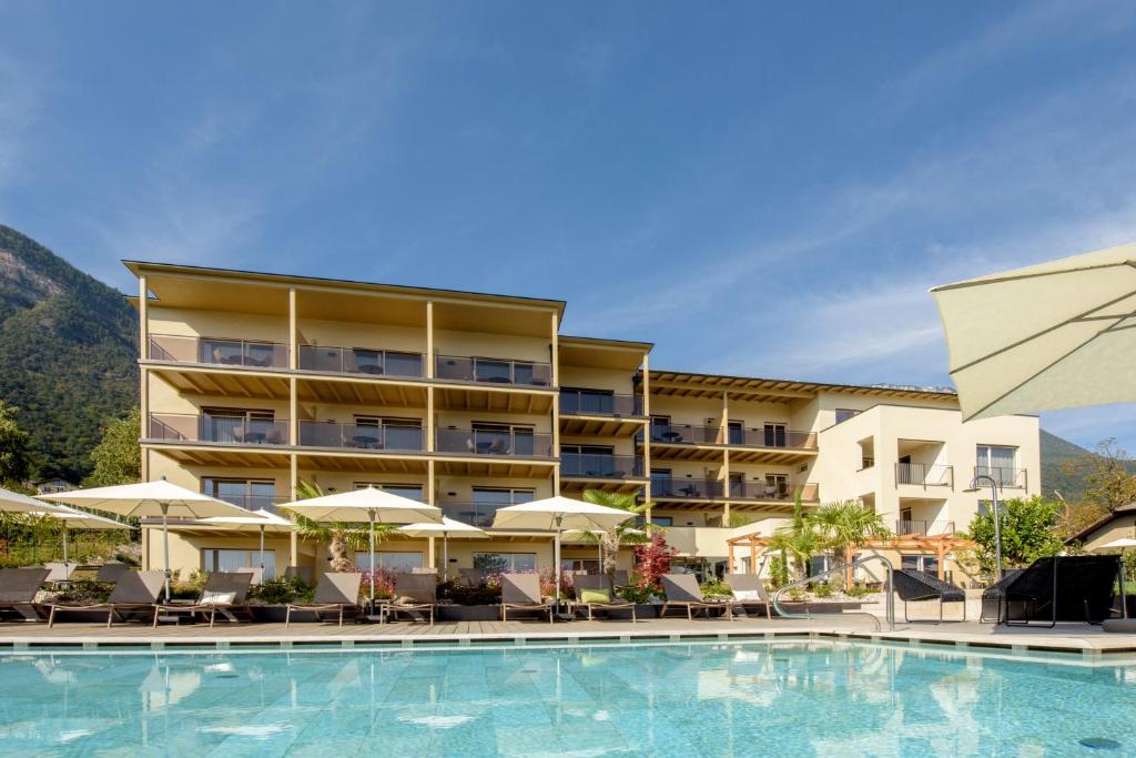 卡尔达罗Brühl Suites&Residence的酒店设有带椅子和遮阳伞的游泳池