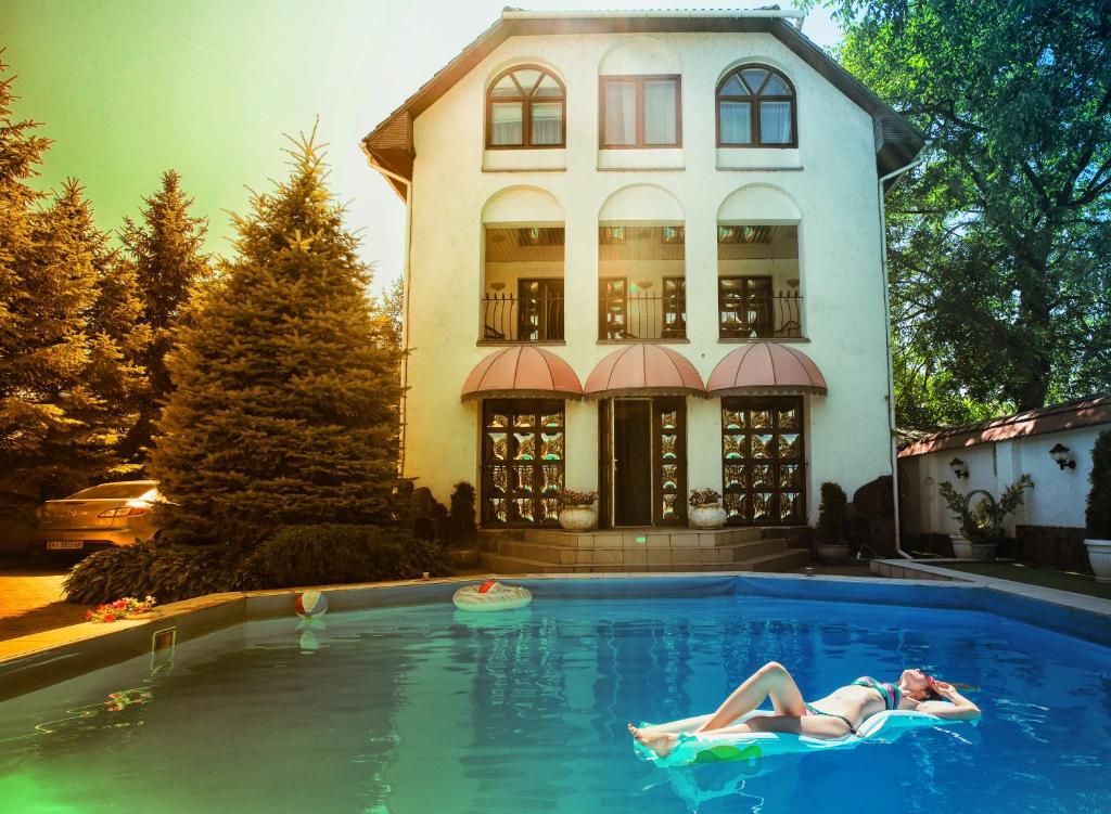 乌日霍罗德Eduard Hotel的躺在房子前面的游泳池中的女人