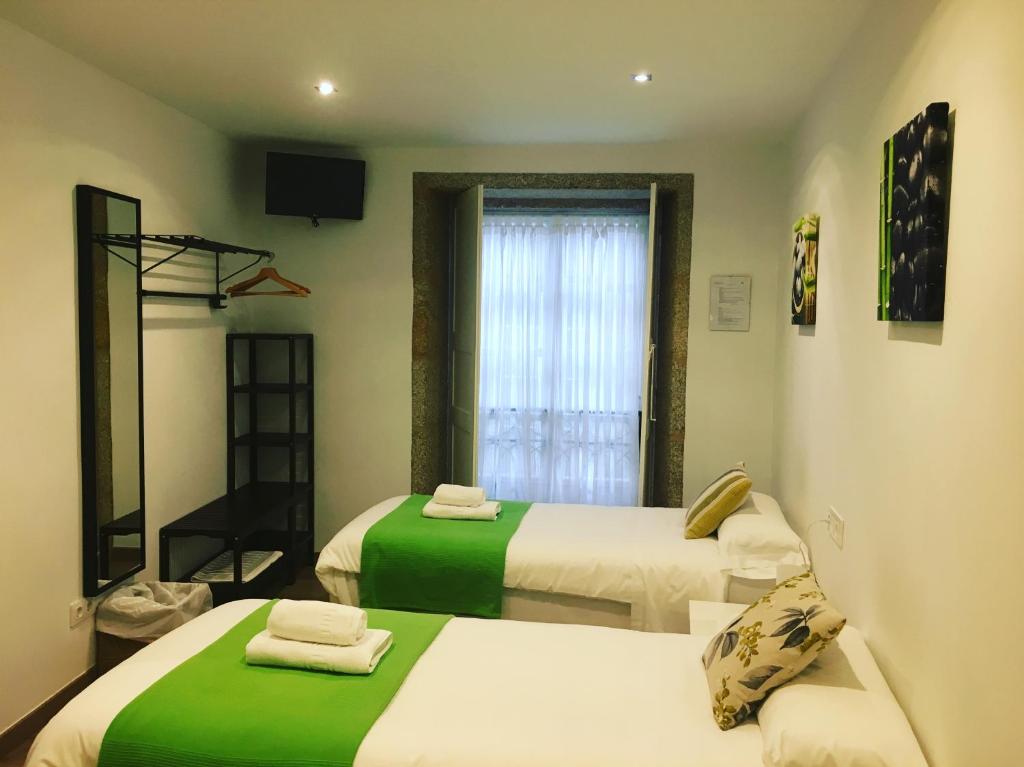 圣地亚哥－德孔波斯特拉丰塞卡旅馆的客房设有两张带绿床单的床和窗户。