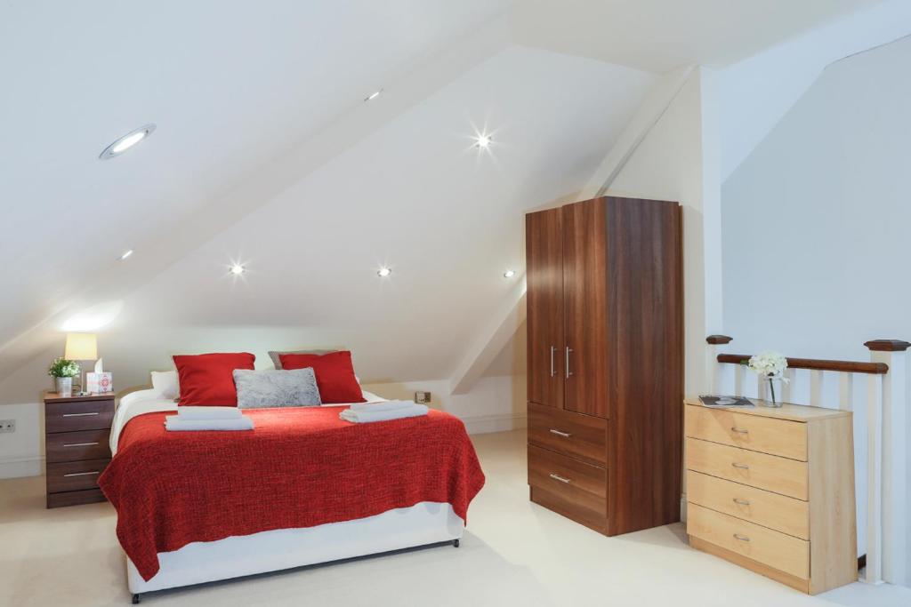 亨顿Finchley Central Spacious 3 bed triplex loft style apartment的一间卧室配有红色的床和木制橱柜