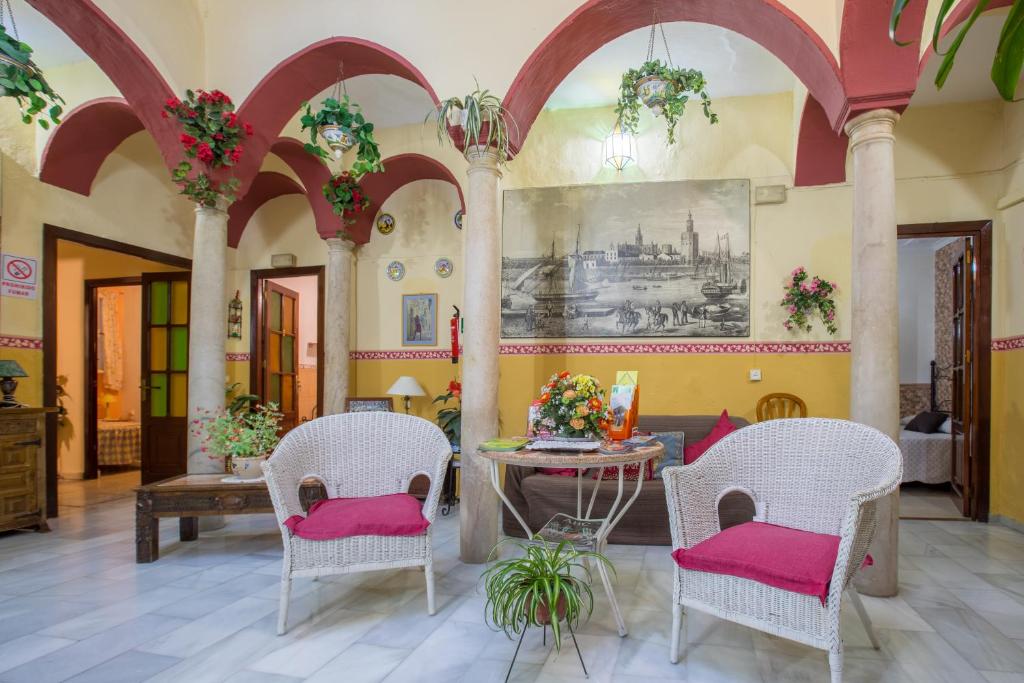 塞维利亚哈维尔膳食公寓的客厅配有两把椅子和一张带粉红色垫子的桌子