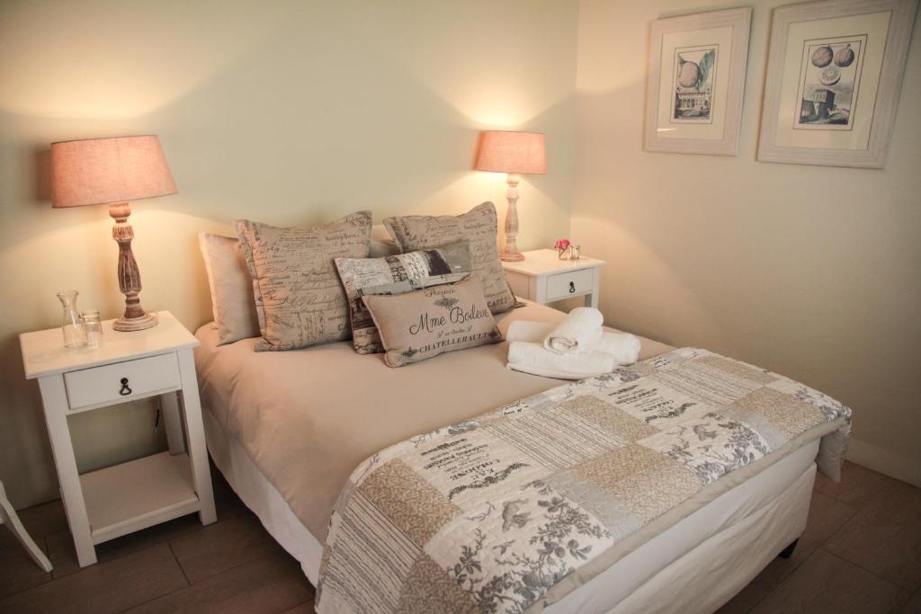 纽卡斯尔Olive Manor Guest House的一间卧室配有一张带2个床头柜和2盏灯的床。