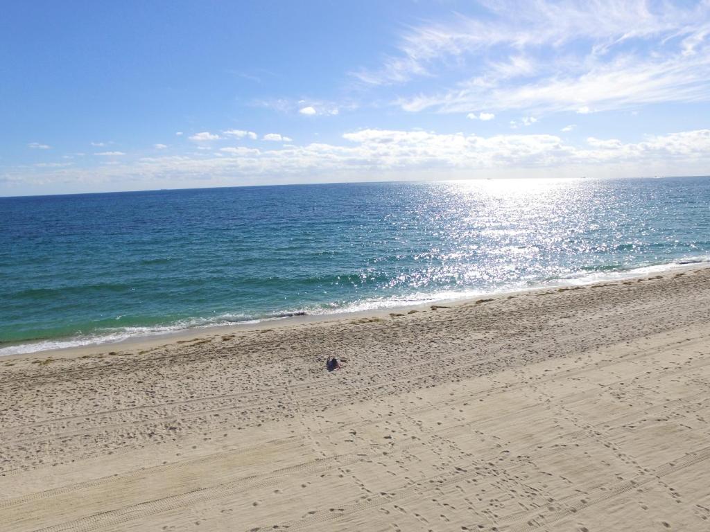 劳德代尔堡佛罗里达最佳度假酒店的一个人在海边的沙滩上散步
