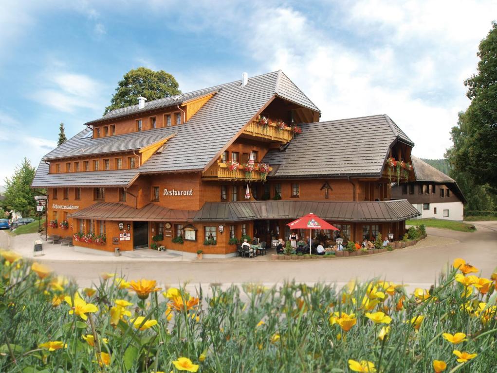 黑林山区贝尔瑙Naturparkhotel Schwarzwaldhaus的一座大型的木质建筑,前面有鲜花