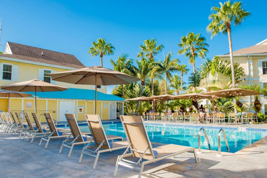 乔治敦阳光套房度假酒店的游泳池旁的一排椅子和遮阳伞