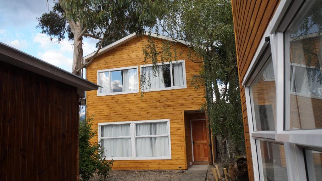 艾森港Patagonia Oley的黄色的房子,有白色的窗户和树