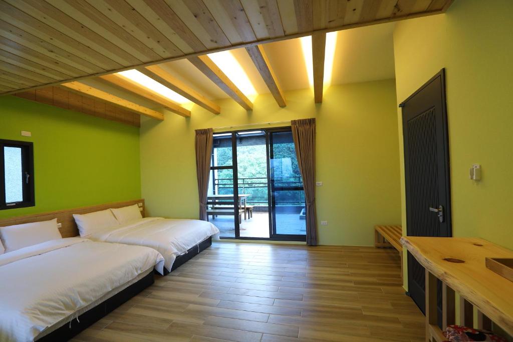 花莲市花莲夏朵民宿的配有绿色墙壁和木地板的客房内的两张床