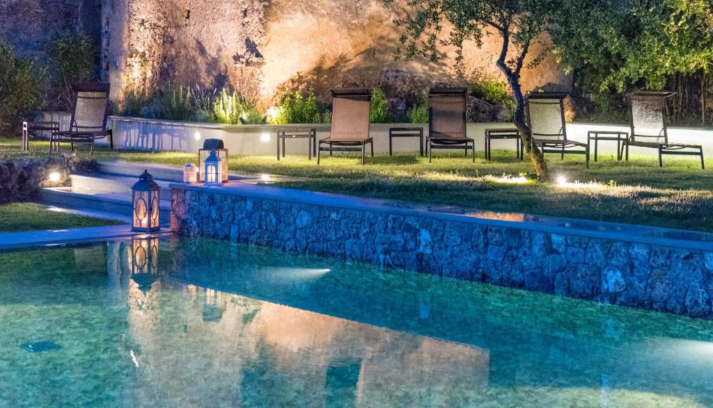 马拉泰亚罗曼蒂克企鹅塔埃利特餐厅酒店的公园里一个带灯光和椅子的游泳池