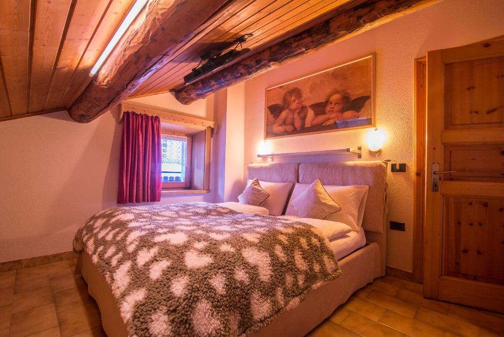 利维尼奥Mansardalpina的卧室配有一张床,墙上挂有绘画作品