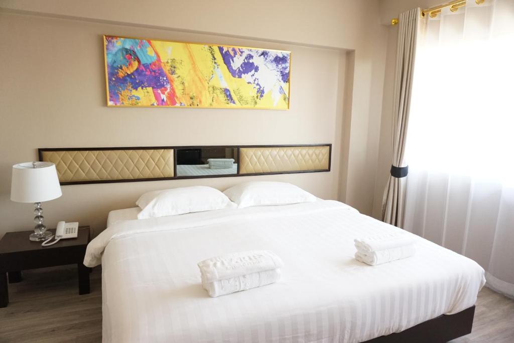 帕府塔拉斯艺术酒店 的一张白色的大床,上面有两条白色毛巾
