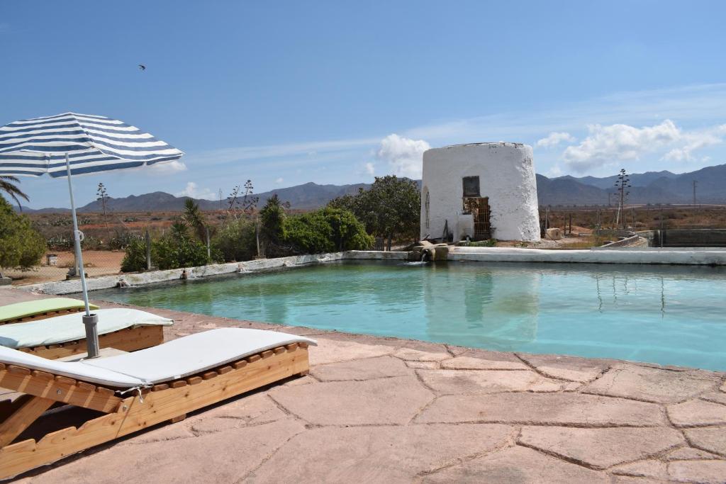 埃尔卡沃德加塔Cortijo La Molina de Cabo de Gata的一个带2把躺椅和遮阳伞的游泳池