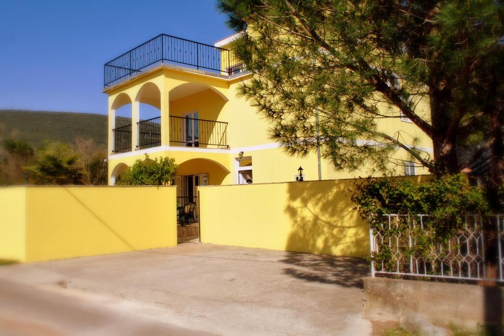 蒂瓦特Apartments Villa-G Lustica的前面有栅栏的黄色房子