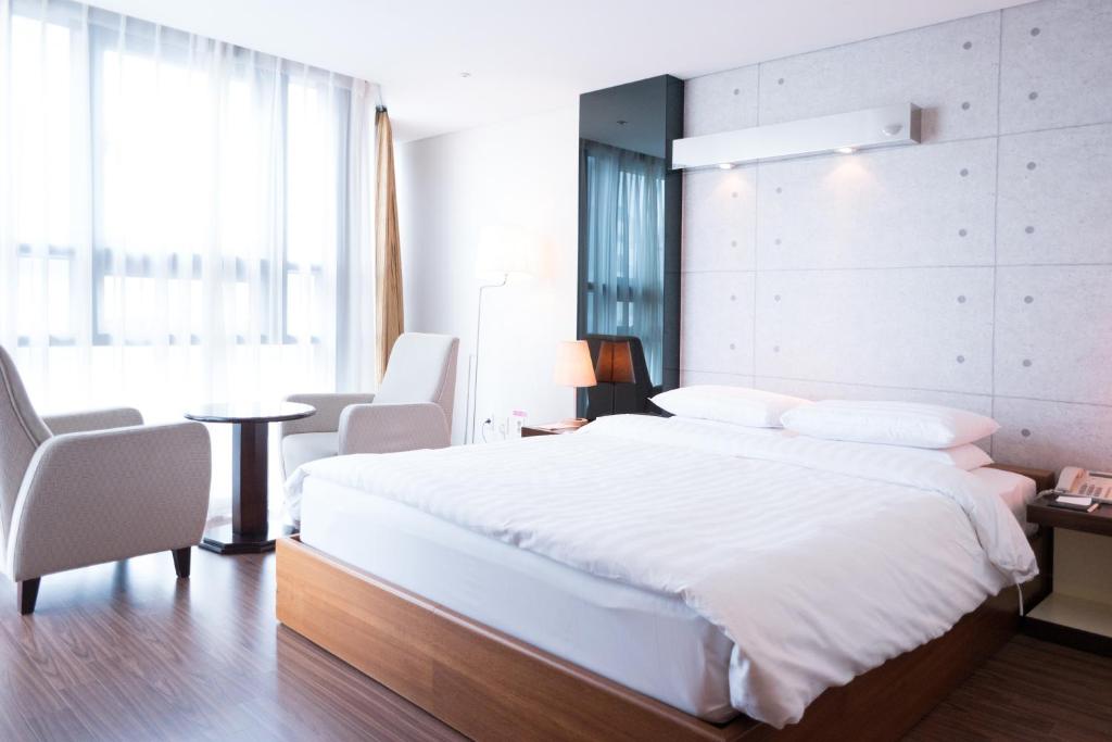 釜山日落商务酒店的卧室配有一张白色大床和一张桌子及椅子
