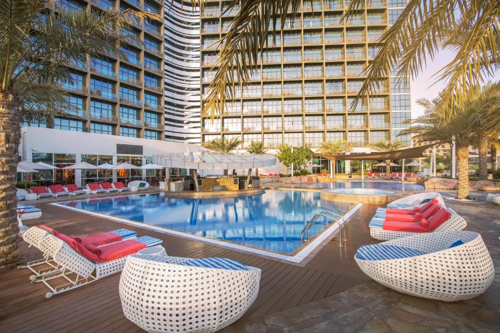阿布扎比阿布扎比亚斯岛罗塔纳酒店的酒店游泳池设有椅子,酒店大楼设有大型游泳池。