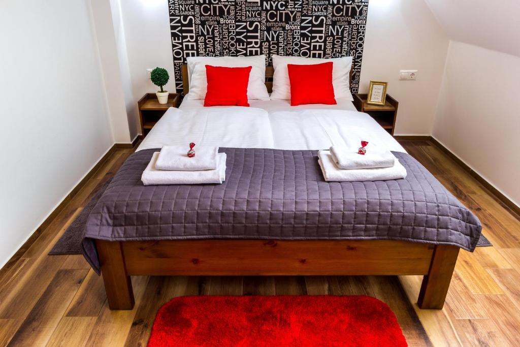 塞格德Aqualiget-Apartmanház的一间卧室配有一张带红色枕头的大床