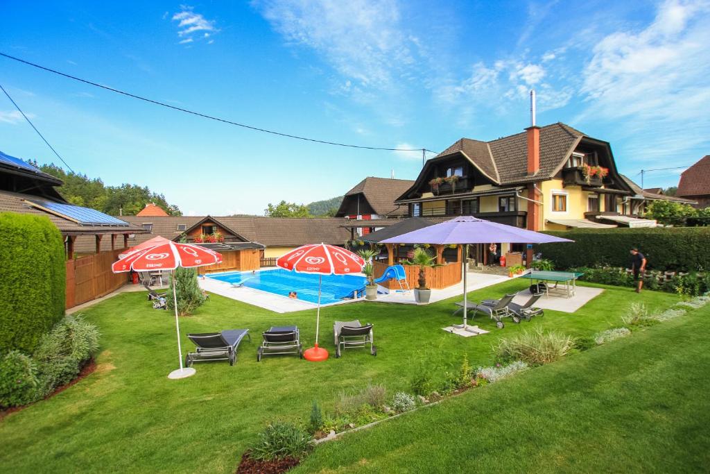 韦尔特湖畔克伦彭多夫皮梭旅馆的一个带游泳池、遮阳伞和房子的后院
