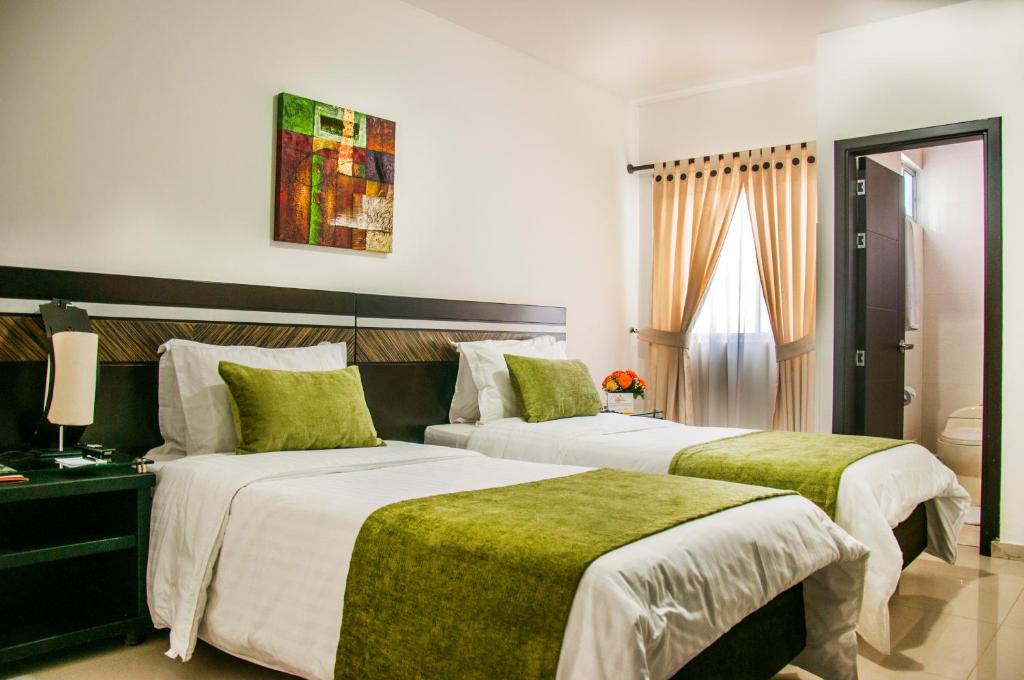 布卡拉曼加圣何塞广场酒店的酒店客房,配有两张带绿床单的床