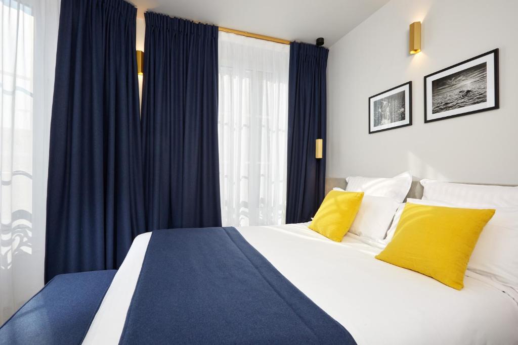 巴黎Hôtel Edouard 6 by Malone的一间卧室配有一张带蓝色窗帘和黄色枕头的床。