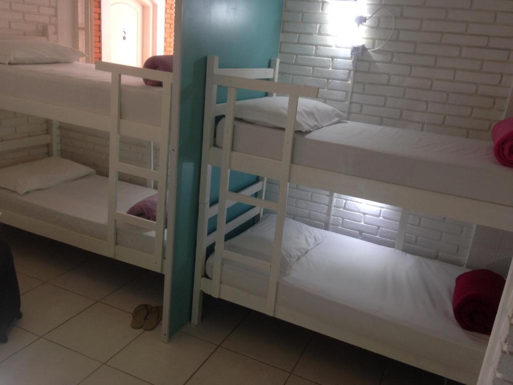 巴乌鲁Black Hotel的一间设有三张双层床和白色架子的房间