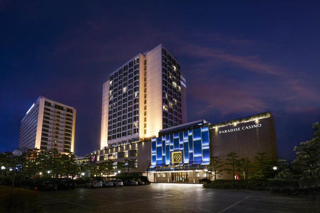 釜山百乐达斯釜山酒店的一座高大的建筑,晚上有蓝色的灯光