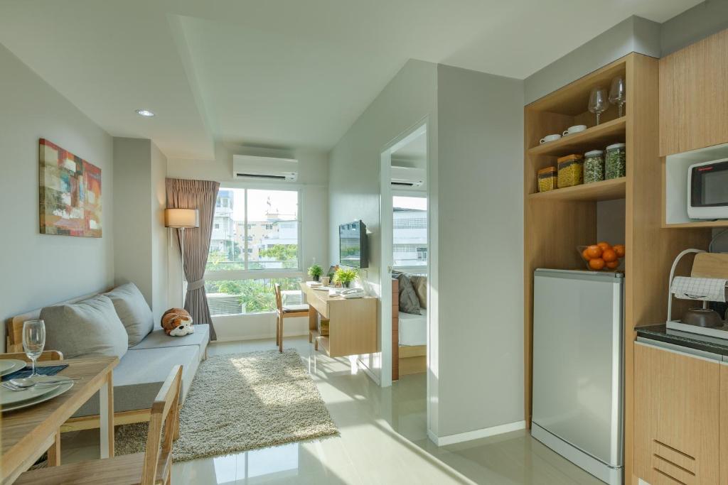 Samut Sakhon通臣公寓酒店的厨房以及带沙发和桌子的客厅。