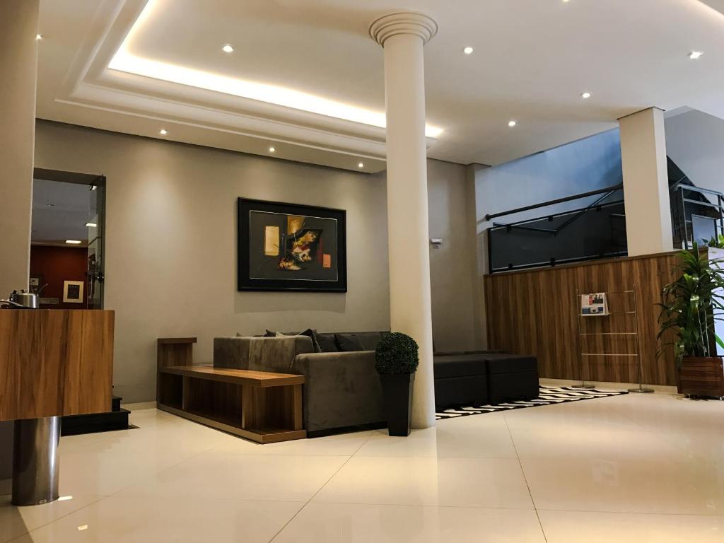 库里提巴Rede Andrade Mercado Hotel的大堂配有沙发和墙上的电视。