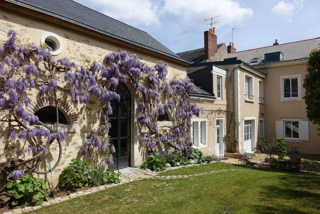 勒芒Chambres d'hôtes Le Clos d'Hauteville的旁边是紫色紫色紫藤的房子