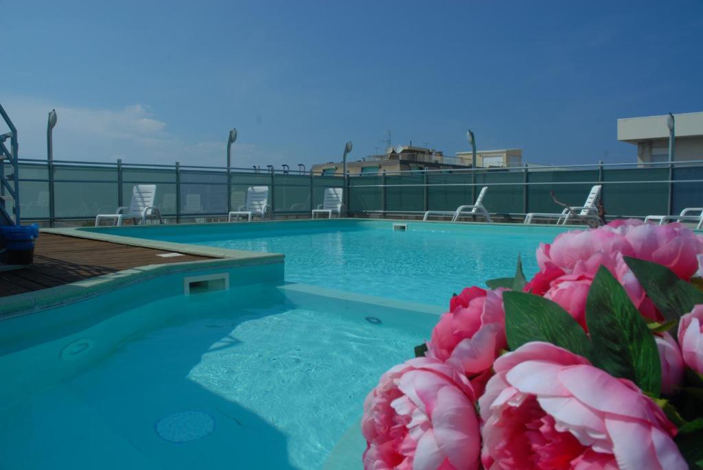 卡托利卡Residence Hotel Club House的前方的游泳池,有粉红色的花朵