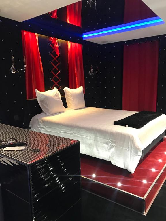 里昂Le Cabaret Vip SPA的一间卧室配有两张带红色和蓝色窗帘的床