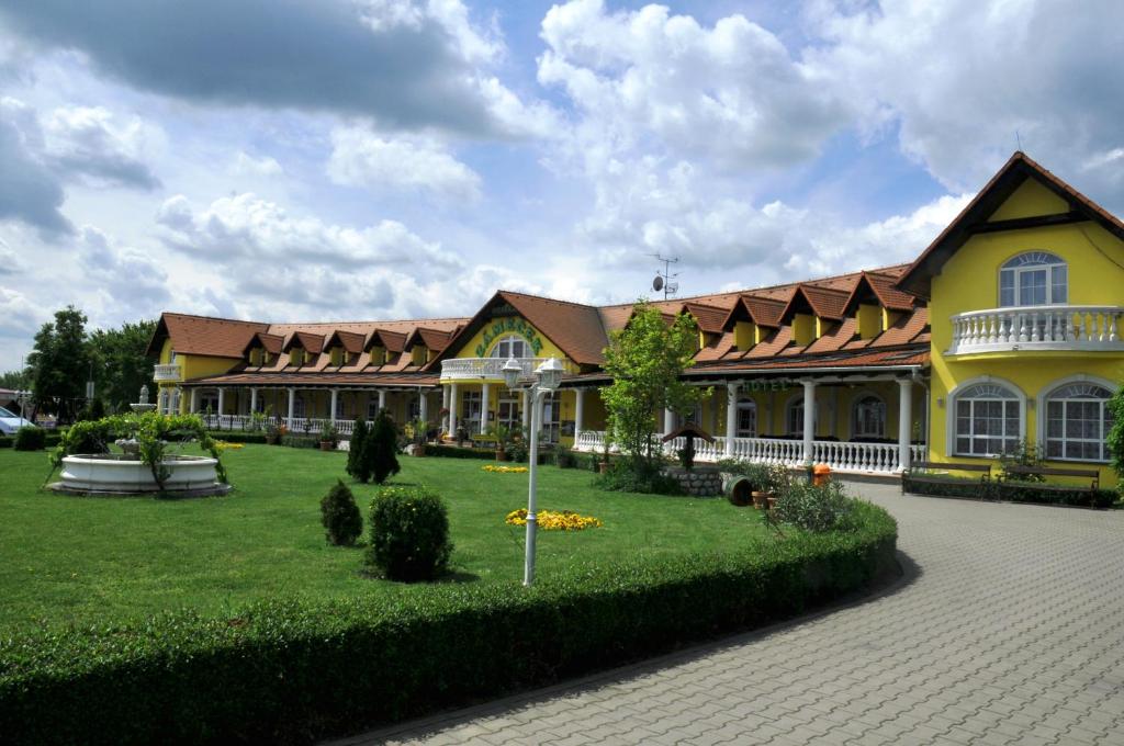 米库洛夫Hotel Zámeček的一座黄色的大建筑,有绿色的院子