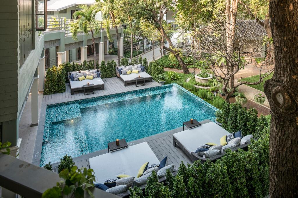 曼谷曼谷拉威坎拉亚酒店的享有带躺椅的游泳池和度假村的顶部景致