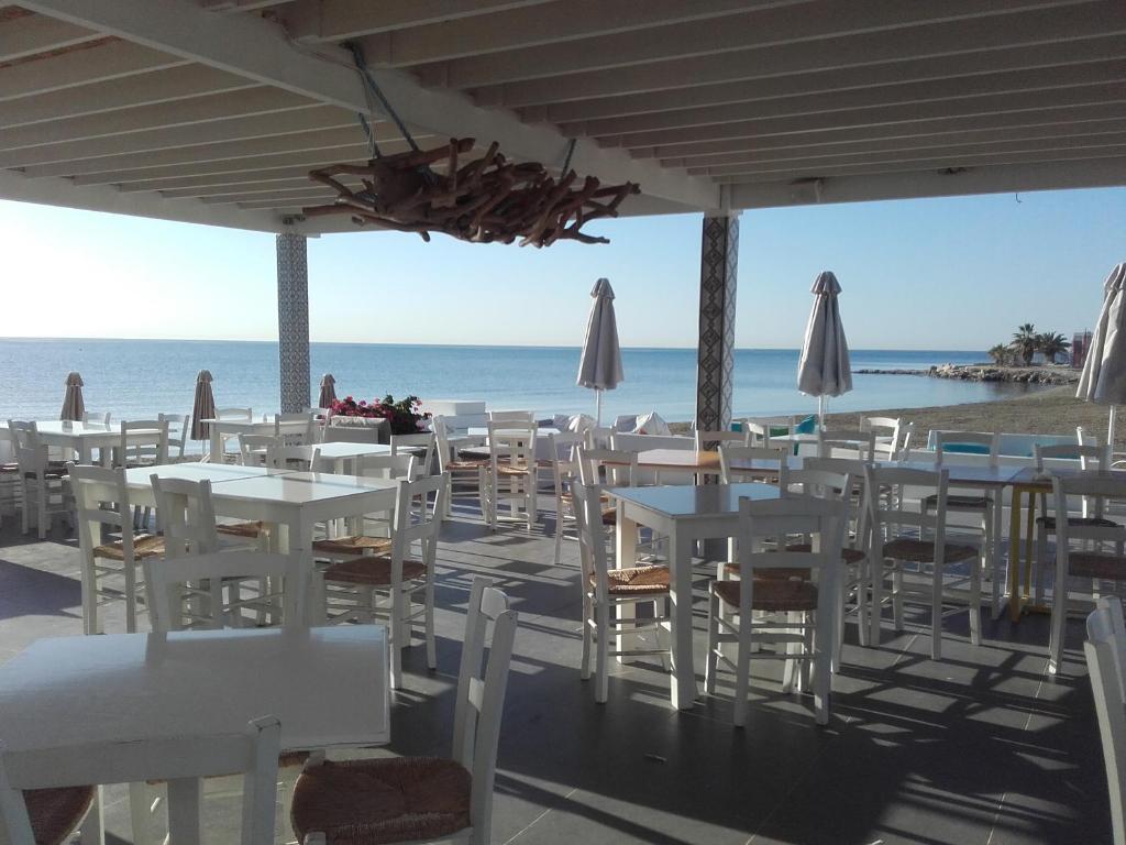 拉纳卡Property Direct Stadem Apartment Second Floor的海滩上设有白色桌椅的餐厅